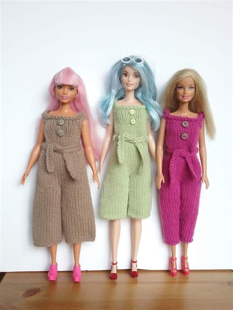 Three Dolls Standing Next To Each Other In Front Of A White Wall With