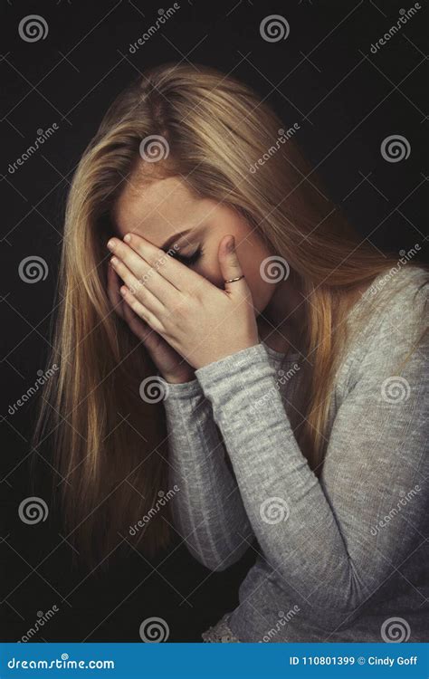 Teenage Girl With Long Blond Hair Crying With Her Hands Up To Her Face