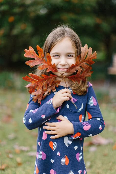 Cute Babe Girl Holding Up A Branch With Leaves To Her Face By Stocksy Contributor Jakob