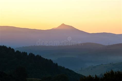 Beautiful Mountain Landscape With Hazy Peaks And Foggy Valley At Sunset