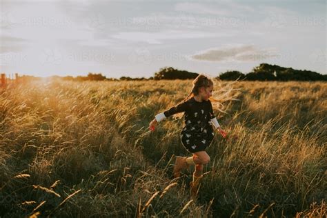 Image Of Young Fashionable Girl Running Through Long Grass In Paddock At Sunset Austockphoto