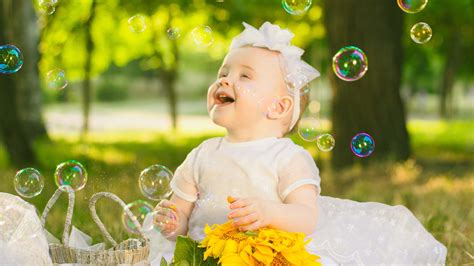 Cute Girl Baby Is Playing With Bubbles Wearing White Dress In Blur