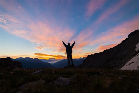 Man Standing On Mountain Top Outstretching Arms Sunrise Light Colorful