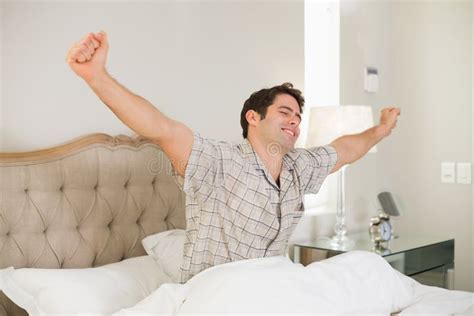Young Man Waking Up In Bed And Stretching His Arms Stock Photo Image