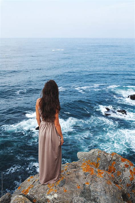 Attractive Girl Standing On The Edge Of A Cliff At The Seashore By