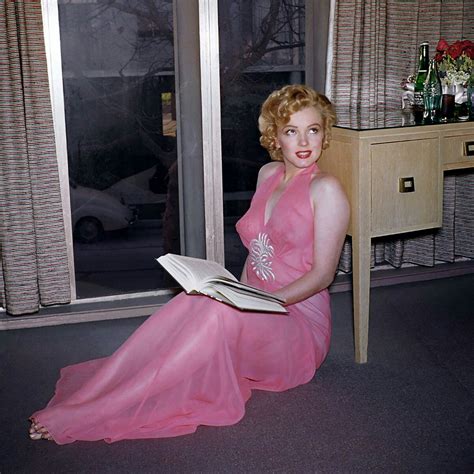Mаrilyn Monroe reаding a book in a see through pink negligee c 1950