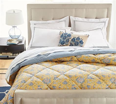 A Bed With White And Blue Comforters In A Bedroom