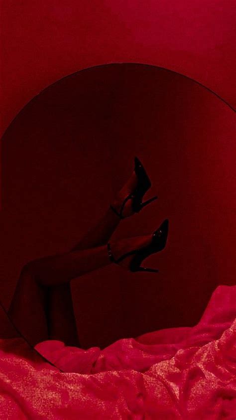 A Woman S Legs In High Heeled Shoes On A Bed With Red Sheets