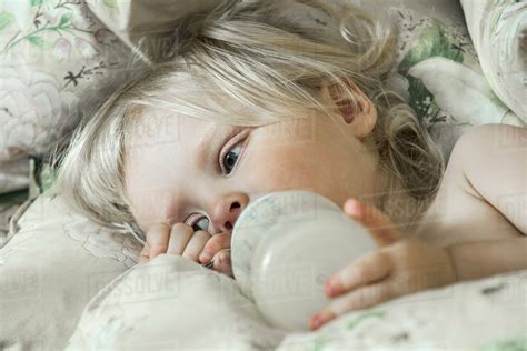 Tired Girl On Bed Drinking From Milk Bottle Stock Photo Dissolve