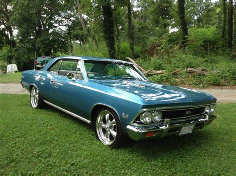 An Old Blue Car Parked In The Grass