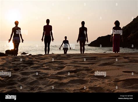 Las Mujeres Que Practican Yoga En La Playa En El Atardecer Fotografía
