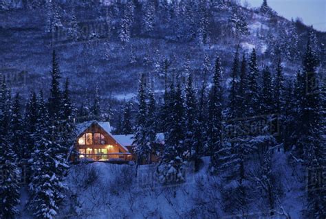 Home Cabin In Snow Covered Forest Lights On Dusk Southcentral Alaska