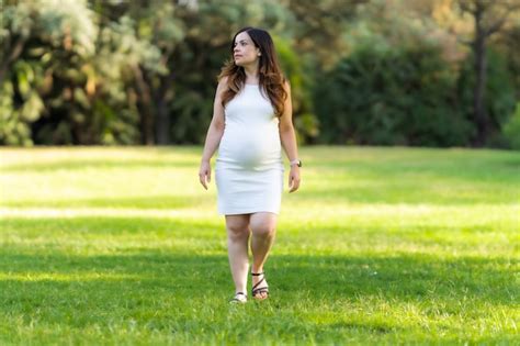 premium photo portrait of an adult pregnant latina woman walking on the grass of a park in a