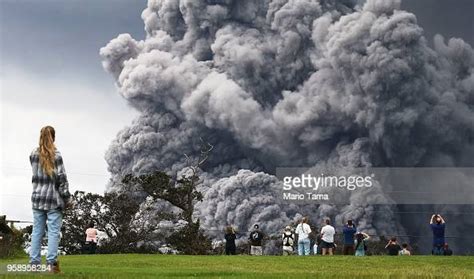 People Watch At A Golf Course As An Ash Plume Rises In The Distance