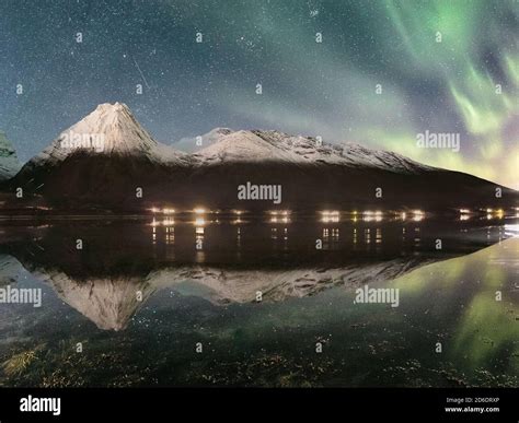 Northern Lights Aurora Borealis Over Above A Snowy Mountain Range In