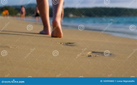 Barefoot Lady Walks Along Empty Ocean Beach Under Blue Sky Stock Photo