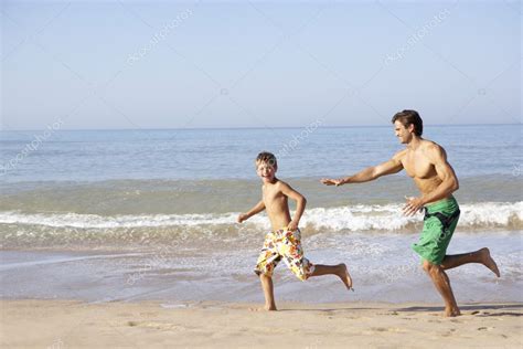 Father Chasing Young Boy On Beach Stock Photo By ©monkeybusiness 11878657