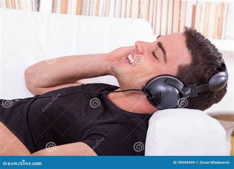 Handsome Man Resting On Couch Listening To Music With Headphones Stock