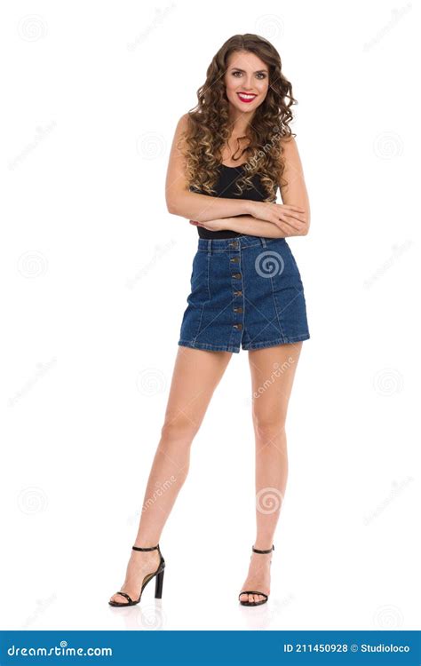 Young Woman In Jeans Mini Skirt Black Top And High Heels Is Standing