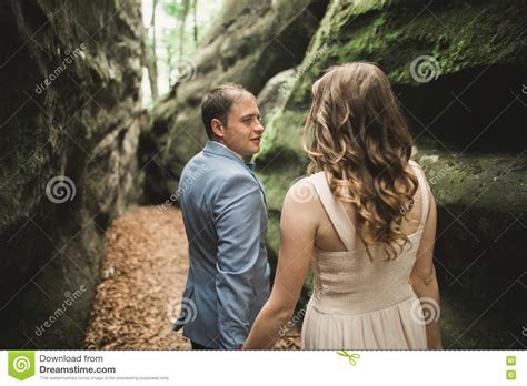 Gorgeous Wedding Couple Kissing And Hugging In Forest With Big Rocks