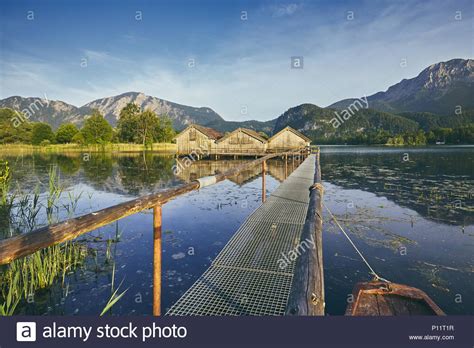 View Of Lake Kochelsee With Wooden Boathouses Against Mountain Range
