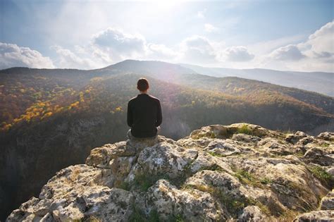 Man Sitting On The Cliff Of Mountain Premium Photo