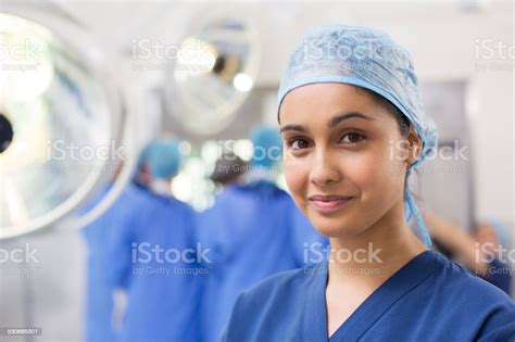 Portrait Of Smiling Female Surgical Nurse Wearing Blue Surgical Cap And
