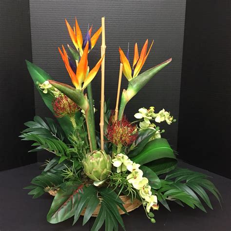 An Arrangement Of Tropical Plants And Flowers In A Basket On A Table