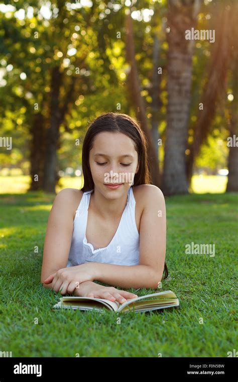 Cute Teen Girl Reading Book Laying On Green Grass In Park Selective