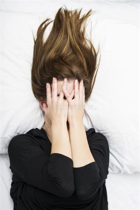 Young Depressed Woman Is Lying In Her Bed Covering Her Face With Her
