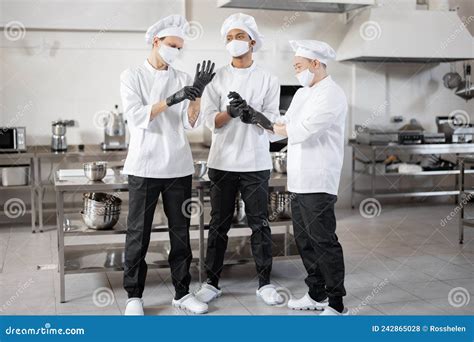 Team Of Chefs Wearing Protective Gloves And Face Masks Preparing For A