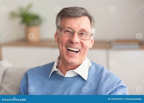 Senior Man Laughing At Camera Sitting On Couch At Home Stock Image