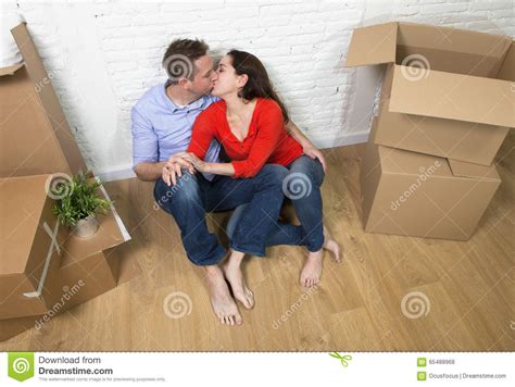 Happy American Couple Sitting On Floor Kissing Celebrating Moving In