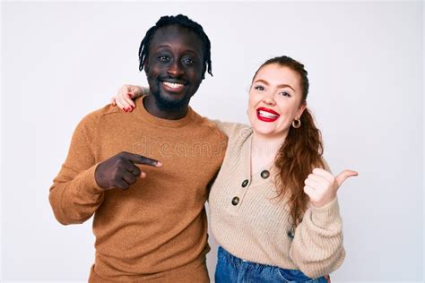 Interracial Couple Wearing Casual Clothes Pointing To The Back Behind