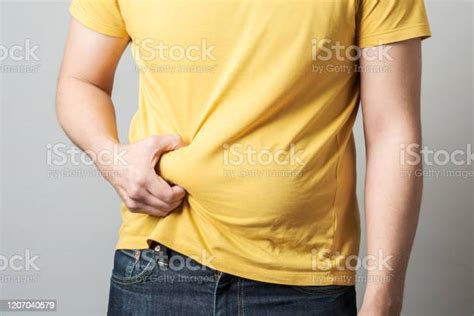 Close Up Of Overweight Obese Mans Hand Holding His Big Belly Isolated