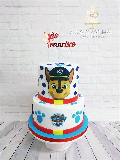 A Three Tiered Cake With A Dog On Top And Paw Print Decorations Is