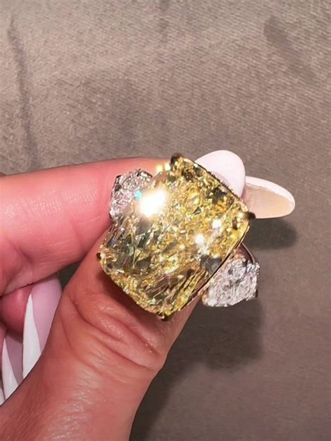 A Fancy Yellow Diamond Ring Being Held By Someone S Hand