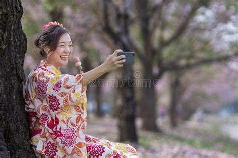 Japanese Woman In Traditional Kimono Taking Selfie Hanami Dango Gesture While Walking In The