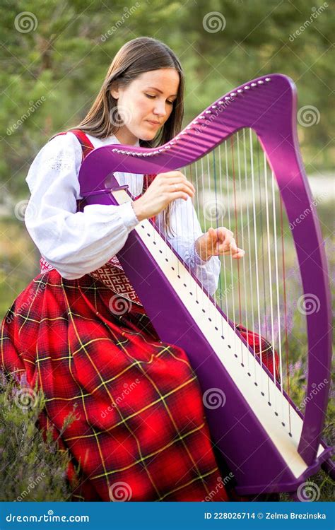 Beautiful Young Woman Playing Celtic Harp And Singing Song In Woodland