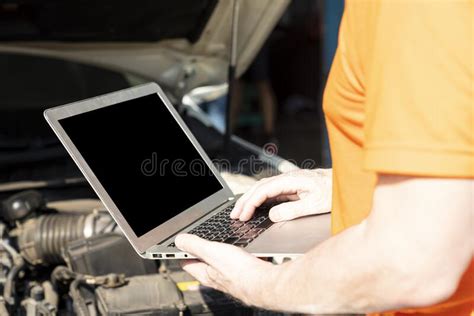 A Car Mechanic Is Using A Laptop Computer To Check The Engine Operation