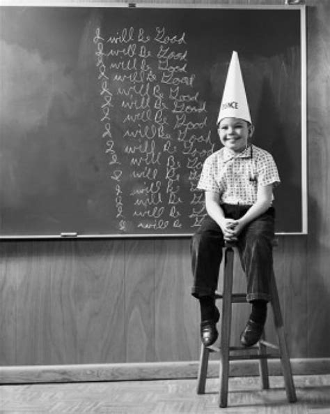 Boy Wearing A Dunce Cap Sitting In Front Of A Blackboard Poster Print