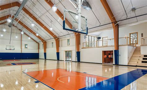 An Indoor Basketball Court With Blue And Orange Flooring In The Middle