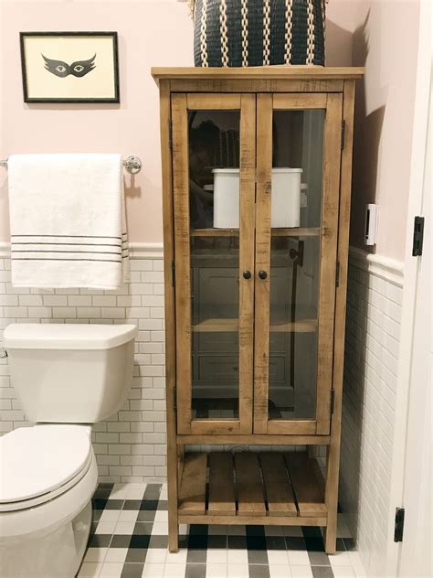 A White Toilet Sitting Next To A Wooden Cabinet In A Bathroom With