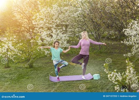 Una Joven Madre Y Su Hija Realizan Ejercicios De Yoga En El Parque En
