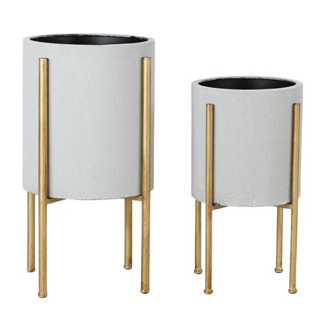 Two White Planters With Gold Handles On Each One And Another In The