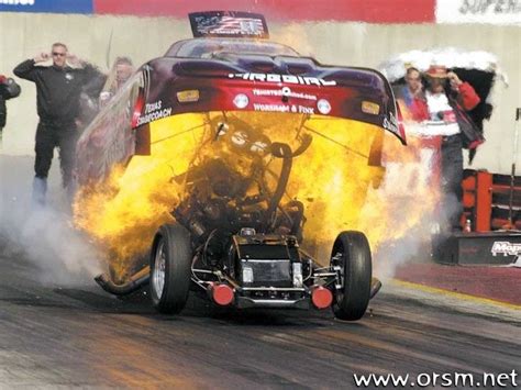 a drag car with yellow flames coming out of it s engine is on fire