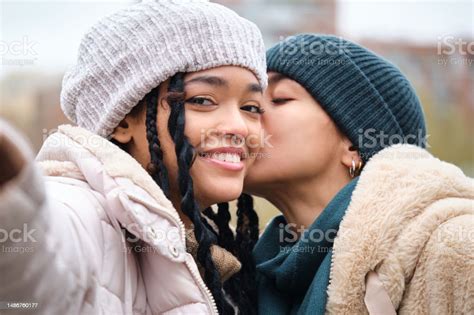 Happy Dominican Lesbian Couple Taking A Selfie While Kissing On The