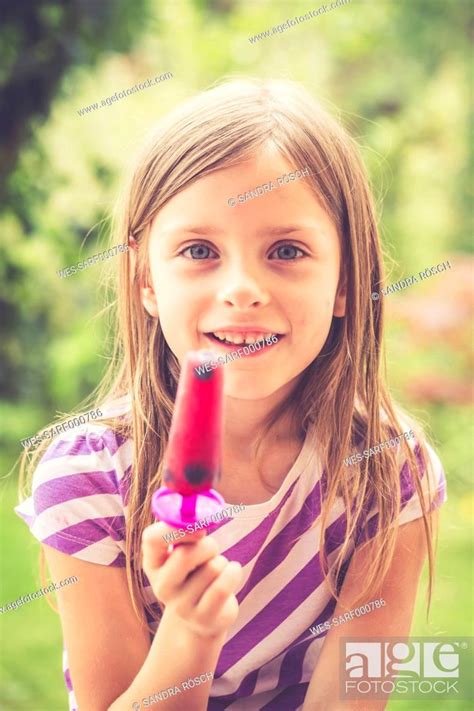 Portrait Of Little Girl With Popsicle In The Garden Stock Photo