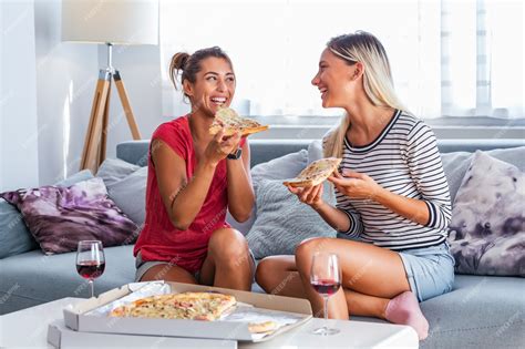 amigas comiendo pizza con vino en el sofá en casa foto premium