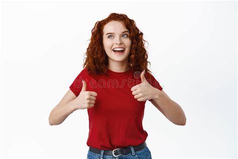 Young Smiling Curly Haired Ginger Girl Show Thumbs Up And Look At Upper